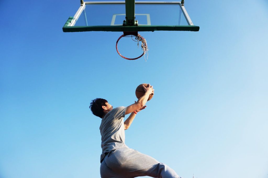 A man playing basketball during a sunny day with a clear blue sky above him.