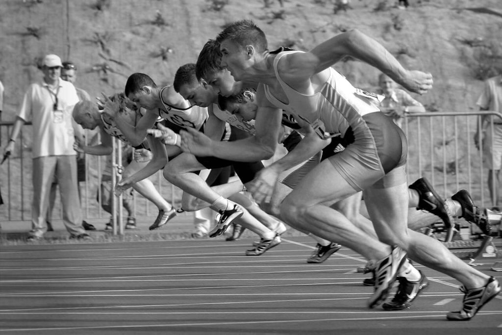 A black and white photo of an explosive start to a race which includes several track sprinters