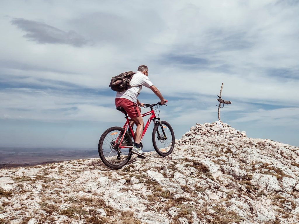Man mountain biking on rocky terrain with a scenic view.